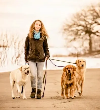 Cassie, Trainer at Ruffin' It Resort, walking three dogs